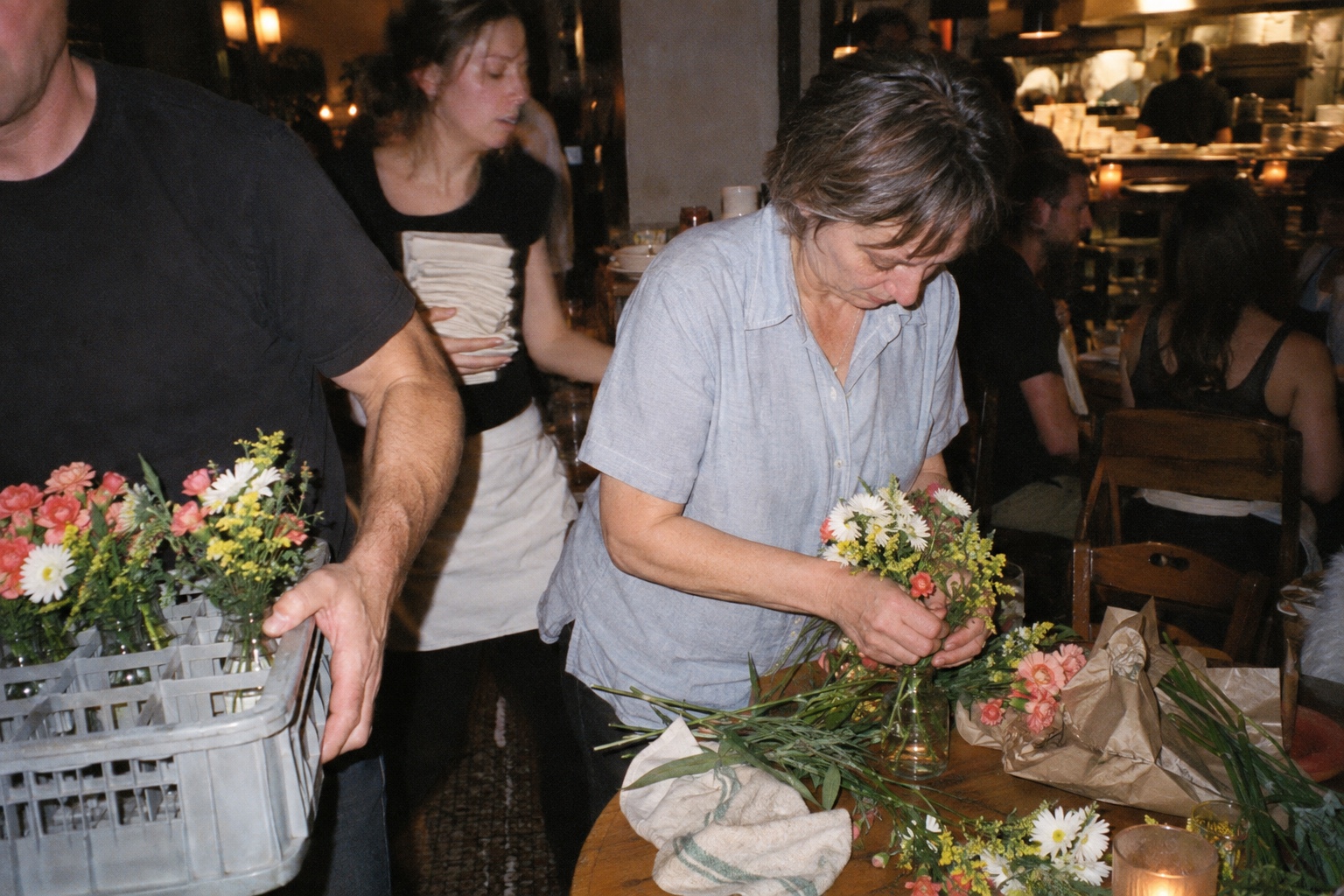 A florist arranging flowers during a busy restaurant installation.